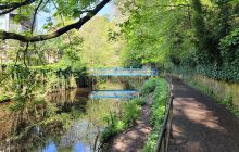 A turquoise footbridge is mirrored on the still waters of the Water of Leith