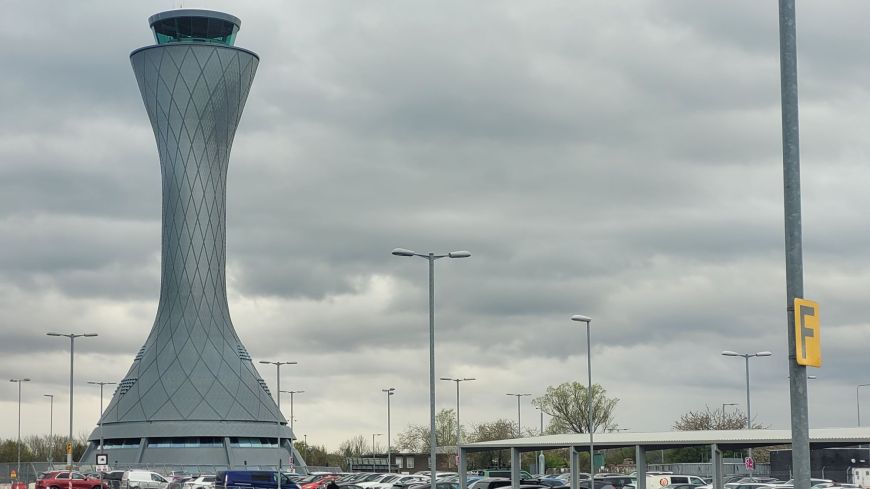 The iconic control tower at Edinburgh airport rises above a car park, against a dusk sky