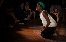 Apphia Campbell, as Mina Bordeaux, kneels in lament.