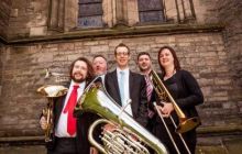 Photo of the five Brass Tracks members posing with their instruments