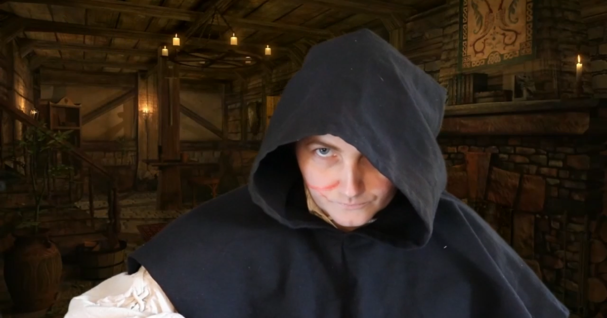 Actor Lexi Wolfe as Henry V with a scar on her face and a hood