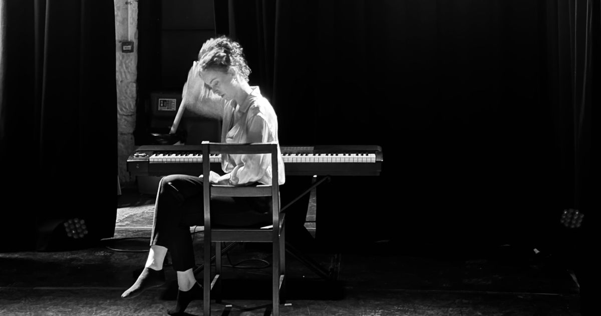 Actor Molly Hanly, pictured sitting sideways on a chair, backlit with light shining through.