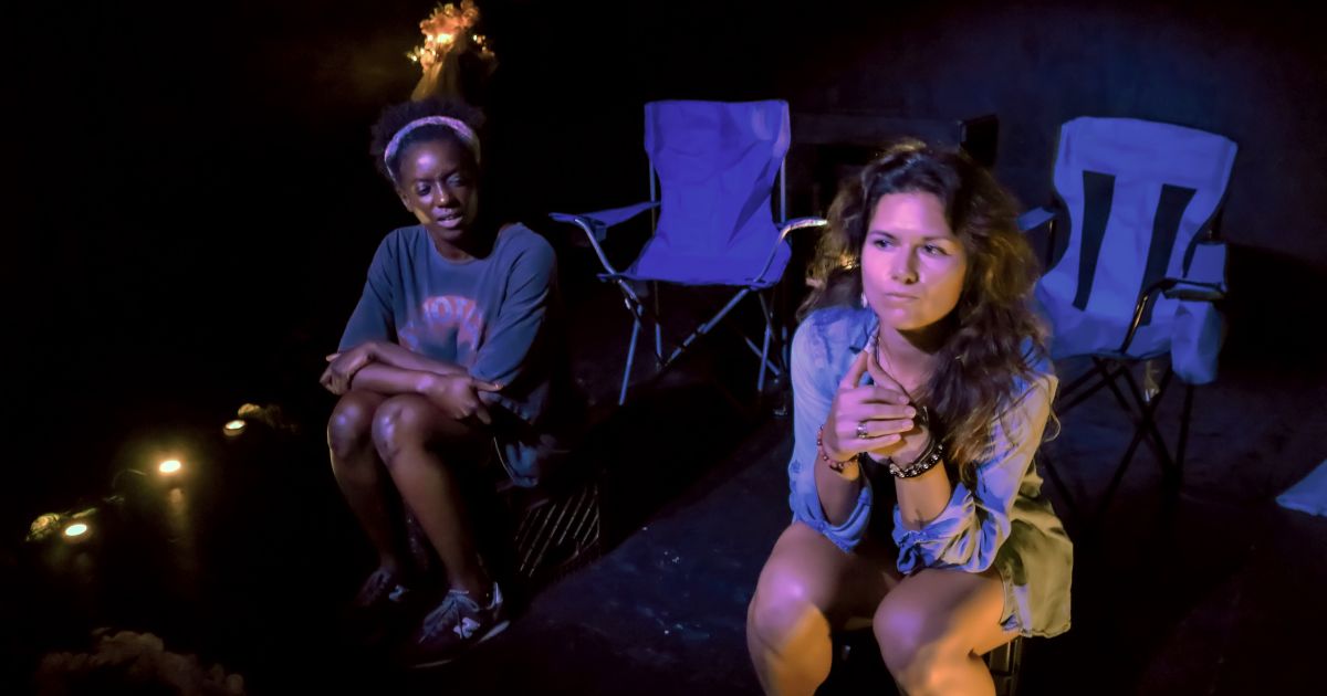 The two actors sit in semi-darkness on folding chairs, looking pensive at the world