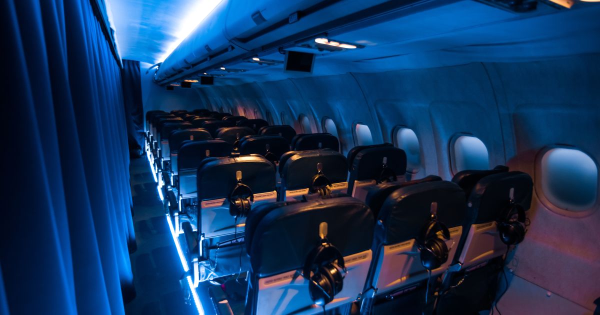Moody blue lighting shows rows of seats in an airplane.