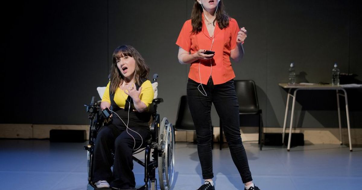 Lisa Hammond (left) and Rachael Spence (right) face the audience, dressed in dark trousers and bright coloured tops. They are contemplating.