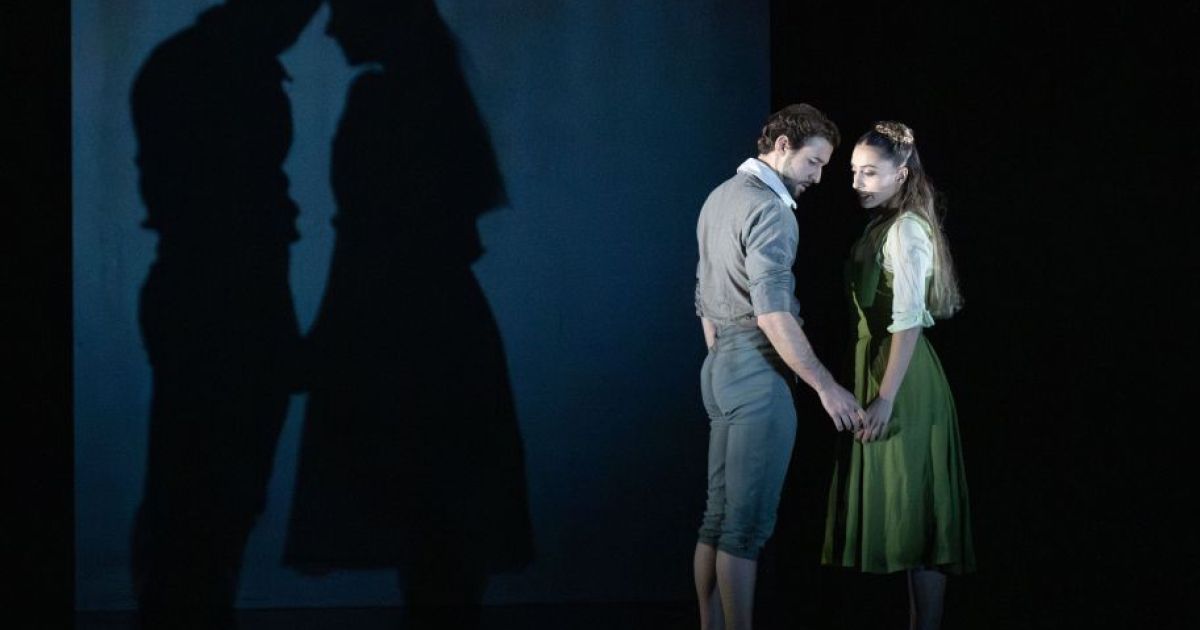 Bruno Micchiardi as John Proctor and Kayla-Maree Tarantolo as Abigail in The Crucible. John is tentatively reaching out to embrace Abigail's hand while their shadows are projected behind them.